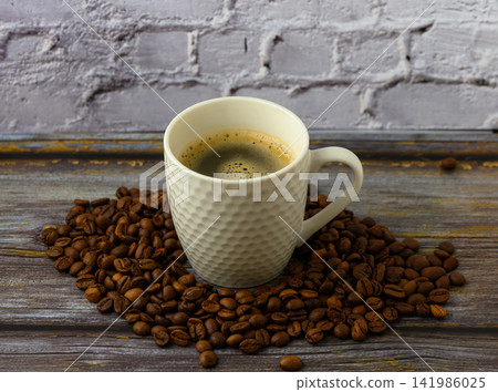 Warm coffee cup resting on a bed of roasted coffee beans in a cozy kitchen setting 141986025