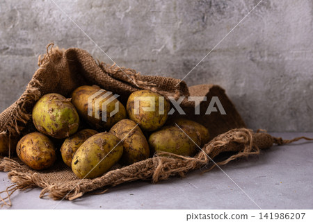 Raw uncooked potato on light background Raw uncooked potato on light background 141986207