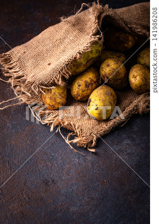 Raw uncooked potato on dark background Raw uncooked potato on dark background 141986208