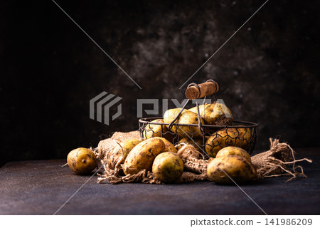 Raw uncooked potato on dark background Raw uncooked potato on dark background 141986209