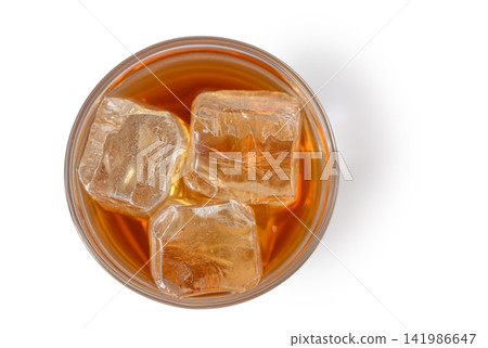Refreshing glass of iced beverage shimmering under warm light with large ice cubes Refreshing glass of iced beverage shimmering under warm light with large ice cubes 141986647