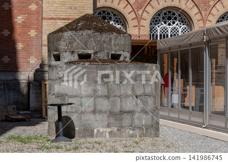 Historic concrete bunker structure standing in courtyard beside brick building Historic concrete bunker structure standing in courtyard beside brick building 141986745