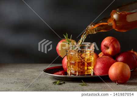 Apple juice is poured from a bottle into a glass. Apple juice is poured from a bottle into a glass. 141987054