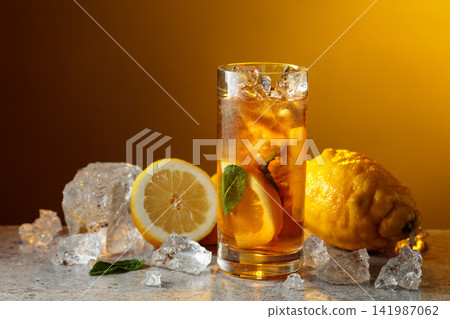 Classic iced black tea in tall glass with lemon wedges, ice cubes and mint leaves. Classic iced black tea in tall glass with lemon wedges, ice cubes and mint leaves. 141987062