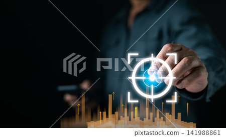 A person interacts with a glowing digital target interface above rising data bars, highlighting analytics precision and modern strategy in a dark tech focused setting boosting future tech growth. A person interacts with a glowing digital target interface above rising data bars, highlighting analytics precision and modern strategy in a dark tech focused setting boosting future tech growth. 141988861