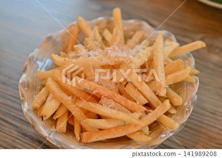 French fries topped with plenty of grated cheese French fries topped with plenty of grated cheese 141989208