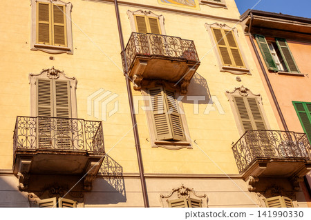 Yellow Historic Building Facade with Wrought Iron Balconies and Shutters Como Italy 141990330