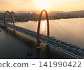 Traffic flows over red bridge as the golden sunset glows off the Qiantang River and the urban skyline. 141990422