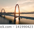 Traffic flows over red bridge as the golden sunset glows off the Qiantang River and the urban skyline. 141990423