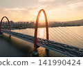 Traffic flows over red bridge as the golden sunset glows off the Qiantang River and the urban skyline. 141990424