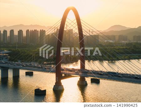 Golden sunset over Hangzhou Qiantang River bridge, with traffic crossing and city skylines reflecting on the water Golden sunset over Hangzhou Qiantang River bridge, with traffic crossing and city skylines reflecting on the water 141990425