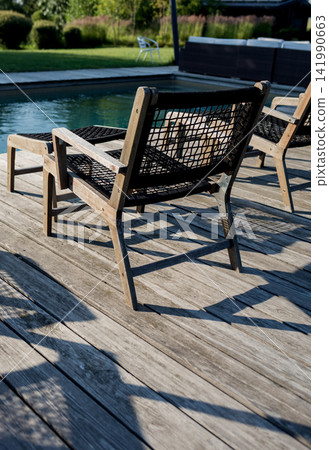 Vertical back view of luxury wooden loungers by swimming pool. Vertical back view of luxury wooden loungers by swimming pool. 141990663