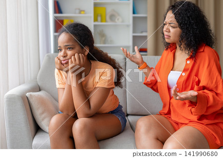 Black mother having a discussion with annoyed teenage daughter on couch Black mother having a discussion with annoyed teenage daughter on couch 141990680