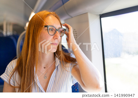 Young woman traveling on train looking out window Young woman traveling on train looking out window 141990947