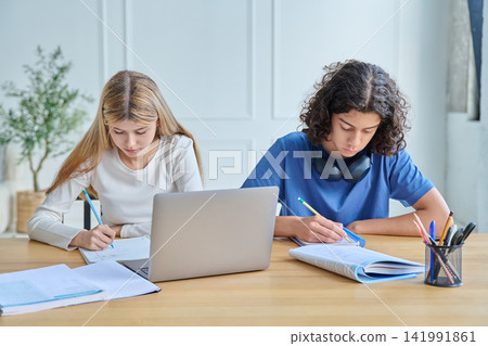Two teen students studying and writing at desk Two teen students studying and writing at desk 141991861