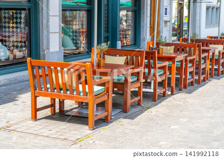 Wooden Chairs and Tables on old Street Outside Cozy European Restaurant Terrace in summer Wooden Chairs and Tables on old Street Outside Cozy European Restaurant Terrace in summer 141992118