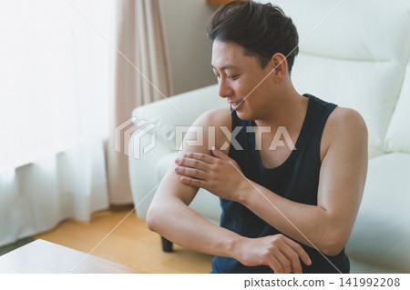 A 40-year-old man smiling while caring for his upper arm: Men's skincare A 40-year-old man smiling while caring for his upper arm: Men's skincare 141992208