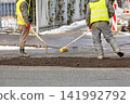 Workers repair a road in a city during daylight hours with tools and equipment 141992792