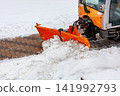 Snow removal at a city street during winter with a snowplow clearing the path 141992793
