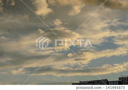 Majestic clouds dance across the evening sky, casting soft shadows over the city skyline at sunset Majestic clouds dance across the evening sky, casting soft shadows over the city skyline at sunset 141993873