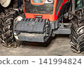 Tractor with large wheels and front attachment for farming work in a barn 141994824