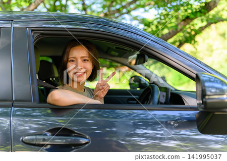 A woman makes a peace sign from her car. A woman makes a peace sign from her car. 141995037