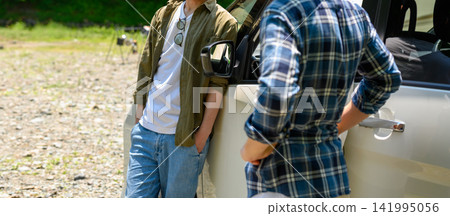 Two men resting in their car at a campsite. Two men resting in their car at a campsite. 141995056