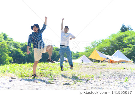 Two men jumping at a campsite Two men jumping at a campsite 141995057