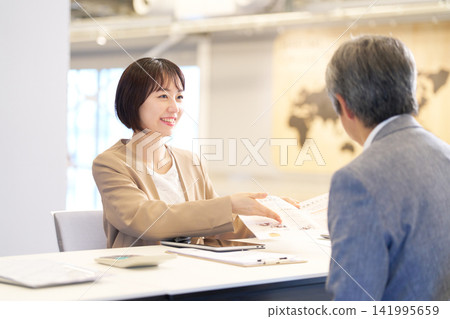 一名女員工和一名資深男士面帶微笑地回應諮詢。 141995659