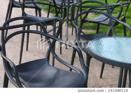 Modern Outdoor Cafe Seating with Stylish Black Chairs and Glass Tables Modern Outdoor Cafe Seating with Stylish Black Chairs and Glass Tables 141996518