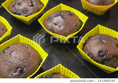 Freshly Baked Chocolate Blueberry Muffins in Yellow Silicone Molds for Perfect Home Baking Freshly Baked Chocolate Blueberry Muffins in Yellow Silicone Molds for Perfect Home Baking 141996544