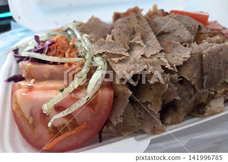 Sliced meat platter with fresh vegetables including tomatoes, cabbage, and onions served in a white takeout container on a table Sliced meat platter with fresh vegetables including tomatoes, cabbage, and onions served in a white takeout container on a table 141996785