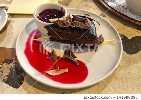 Decadent Chocolate Cake with Cherry Sauce and Artistic Chocolate Shavings 141996885