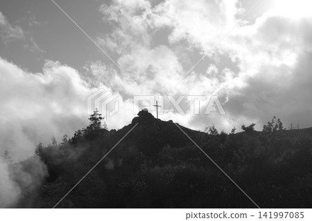 Clouds hanging over the mountains and a cross Clouds hanging over the mountains and a cross 141997085
