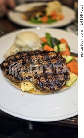 Grilled Ribeye Steak with Herb Butter, Mashed Potatoes and Roasted Vegetables on Plate Grilled Ribeye Steak with Herb Butter, Mashed Potatoes and Roasted Vegetables on Plate 141997119