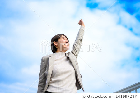 A woman makes a triumphant gesture towards the sky. A woman makes a triumphant gesture towards the sky. 141997287