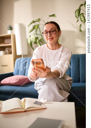 Smiling mature woman showing successful transaction on smartphone Smiling mature woman showing successful transaction on smartphone 141997415