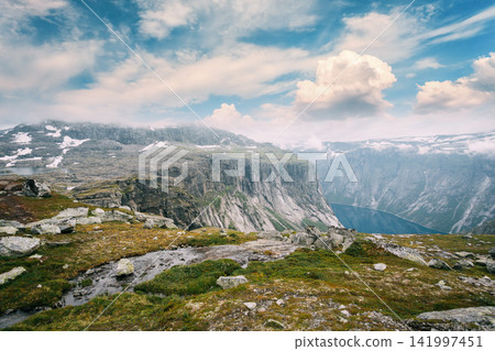 rocky plateau with a stream overlooking a deep lake valley. 141997451