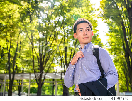 A businessman stands in the park, bathed in dappled sunlight. A businessman stands in the park, bathed in dappled sunlight. 141997592