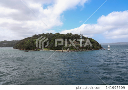 Coastal Headland with Lighthouse and Green Trees Over Blue Ocean Coastal Headland with Lighthouse and Green Trees Over Blue Ocean 141997609