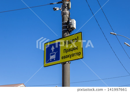 Yellow tow truck warning road sign mounted on a utility pole against a clear blue sky, illustrating strict traffic enforcement, public parking compliance, and urban safety regulations Yellow tow truck warning road sign mounted on a utility pole against a clear blue sky, illustrating strict traffic enforcement, public parking compliance, and urban safety regulations 141997661