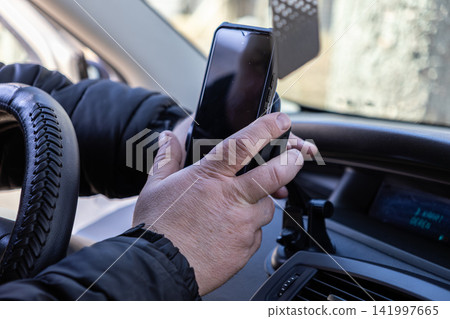 A person secures a smartphone into a dashboard mount inside a car, demonstrating convenience and modern mobile technology integration for navigation during a daily morning commute 141997665