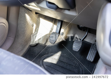Manual transmission car floor pedals including clutch and brake and accelerator viewed from above to represent driving control and mechanical operation in a modern road vehicle Manual transmission car floor pedals including clutch and brake and accelerator viewed from above to represent driving control and mechanical operation in a modern road vehicle 141997672
