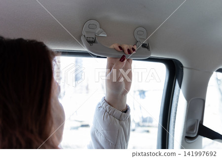 A passenger firmly grips the overhead assist handle inside a moving vehicle to emphasize safety and stability during daily commutes while traveling across busy urban city streets A passenger firmly grips the overhead assist handle inside a moving vehicle to emphasize safety and stability during daily commutes while traveling across busy urban city streets 141997692