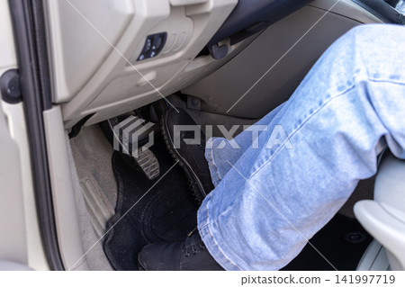 Person in black boots pushes a car brake pedal with their right foot inside a vehicle, highlighting safety, traffic control, and defensive driving techniques for modern road travel Person in black boots pushes a car brake pedal with their right foot inside a vehicle, highlighting safety, traffic control, and defensive driving techniques for modern road travel 141997719