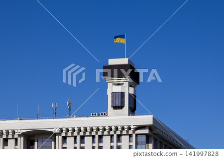 Ukrainian national flag flying atop the Ministry of Transport and Communications building under a clear blue sky, symbolizing national identity, resilience, and sovereignty in Kyiv Ukrainian national flag flying atop the Ministry of Transport and Communications building under a clear blue sky, symbolizing national identity, resilience, and sovereignty in Kyiv 141997828