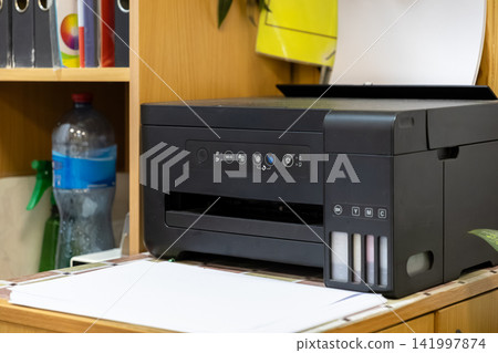 Modern inkjet printer with an integrated ink tank system sitting on a wooden office desk, symbolizing efficient documentation and high quality printing technology for busy workspaces Modern inkjet printer with an integrated ink tank system sitting on a wooden office desk, symbolizing efficient documentation and high quality printing technology for busy workspaces 141997874