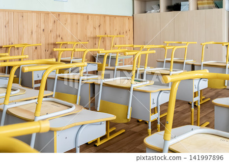 An empty primary school classroom features yellow desks stacked with chairs placed on top to reflect the quiet academic downtime during a long summer vacation break for students An empty primary school classroom features yellow desks stacked with chairs placed on top to reflect the quiet academic downtime during a long summer vacation break for students 141997896