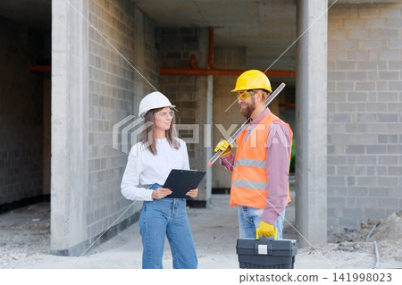 Construction workers discussing blueprint at building site Construction workers discussing blueprint at building site 141998023