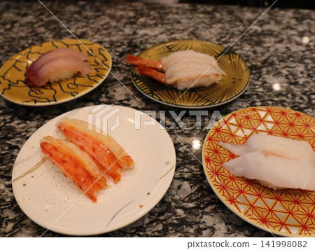 Plates of nigiri sushi lined up on the conveyor belt sushi counter: Yellowtail, sweet shrimp, crab Plates of nigiri sushi lined up on the conveyor belt sushi counter: Yellowtail, sweet shrimp, crab 141998082